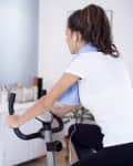 Sporty woman training on exercise bike in the living room
