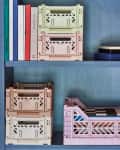 Books and pastel storage crates on blue shelves, with a speaker and a container of colored pencils.