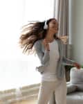 Woman wearing headphones dancing in living room
