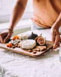 Person sets down appetizer cheese board at a dinner party