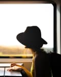 Woman wearing hat looking out train window