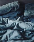 Messy unmade bed with blue sheets