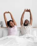 Couple in bed together stretching