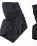 Two pairs of folded black leggings on a white wooden surface.