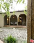 Mediterranean-style courtyard with arched entry, stone path, and potted plants.