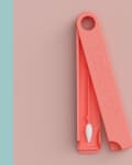 Turquoise and coral reusable swabs in matching cases, each with a looped handle.