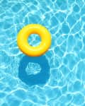 Yellow inflatable ring floating in a clear blue swimming pool.
