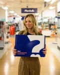 Woman holding a Marshalls Surprise Box in a store aisle.