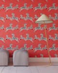 Zebra-patterned wallpaper on a red wall with two striped ottomans and a tall floor lamp.