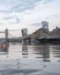 Small house submerged in the Thames River with Tower Bridge and city skyline in the background.
