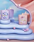 Three decorative candles on pastel blue platform with butterflies and abstract background.