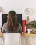 Young woman with headphones facing computer at home
