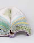 Open geode with colorful crystal layers in green, blue, and yellow hues.
