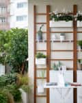 Balcony with vertical garden, white table and chairs, potted plants, and city view.
