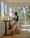Woman working at standing desk in room with lots of windows