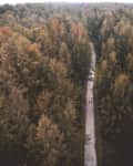 Aerial view of a narrow path cutting through a dense forest with two people walking.