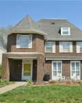 Two-story brick house with a gabled roof, white trim, and a yellow front door.