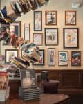 Books spiraling upward on a table with framed vintage posters on the wall in a cozy room.