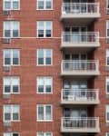 Red brick apartment building with multiple balconies and white railings.