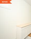 Unfinished laundry room with white cabinets, wooden countertop, and two windows overlooking a lake.