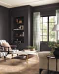 Living room with dark walls, striped armchairs, a coffee table, and a decorative fireplace.