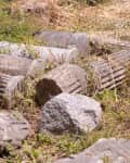 Ancient stone columns and large rocks scattered on grassy ground.