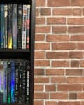 DVD collection on a dark wooden shelf against a brick wall, featuring various movie titles.