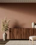 Cozy living space featuring a wooden sideboard, beige armchair with ottoman, decorative vases, and a tall plant.