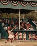 Baseball game with a female batter in a vintage uniform, catcher, umpire, and spectators in a green wooden stadium.