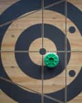 Wooden shuffleboard with black target markings and green pucks.
