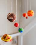 Colorful clay planets hanging from strings, resembling a solar system mobile.