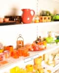 Shelves filled with colorful home decor items, including vases, candles, and small planters in orange, green, and blue.