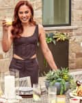 Ayesha Curry in front of a table with her Pottery Barn Sweet July collection of dishes and her lazy susan