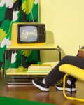Person watching vintage t.v on Ikea coffee table in yellow Ikea chair.