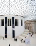 Interior of the British Museum with a glass dome ceiling and central rotunda, surrounded by visitors.
