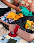 shot of someone folding clothes in a suitcase.