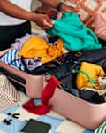 shot of someone folding clothes in a suitcase.