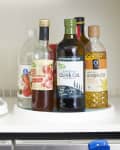 2 lazy susans on a shelf holding various condiment bottles