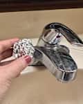 Someone using ball of aluminum foil to clean bathroom faucet.