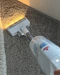 PowerClean Cordless Stick Vacuum in use on a carpeted surface.