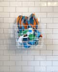 White wire basket on tiled wall holding blue and orange snorkel gear.