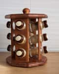 Wooden spice rack with glass jars on a kitchen counter.