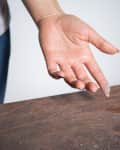 Close-up of dust on woman's finger taken from wooden table