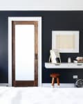 Bedroom with dark walls, a wooden door, green velvet chair, wall-mounted desk, and a large mirror.