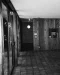 Spacious room with wood paneling, tiled floor, hanging globe lights, and a small kitchen area.