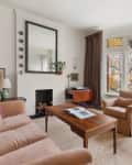 living room with bay window and window seat, stained glass details, accent chair with small round table, brown large sofa, wood coffee table