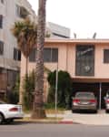 Two-story apartment building with palm trees, three parked cars, and a sign reading "Florentine" above the entrance.