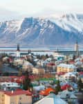 Colorful rooftops of Reykjavik with snow-capped mountains in the background.