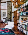 Cozy living room with a blue sofa, white armchair, colorful rug, bookshelves, and a stone fireplace.