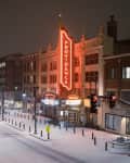 Historic theater with illuminated "Providence" sign on snowy street at night.
